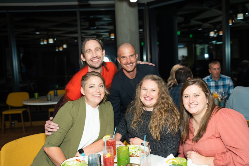 A group of six adults pose for a photo inside of a restaurant