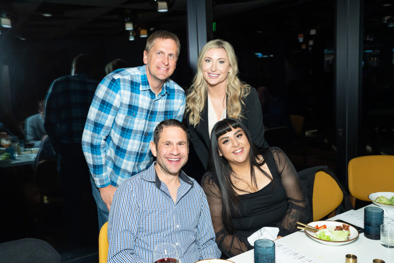 Four smiling people are posing at a table in IMAGE Studios